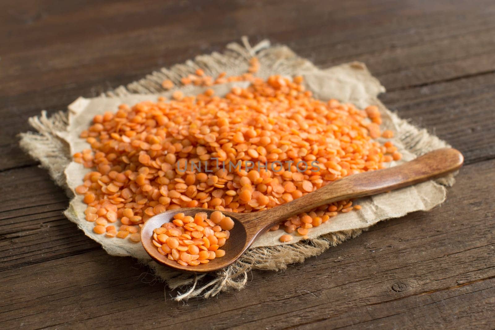 Red lentils with a spoon close up on wooden table