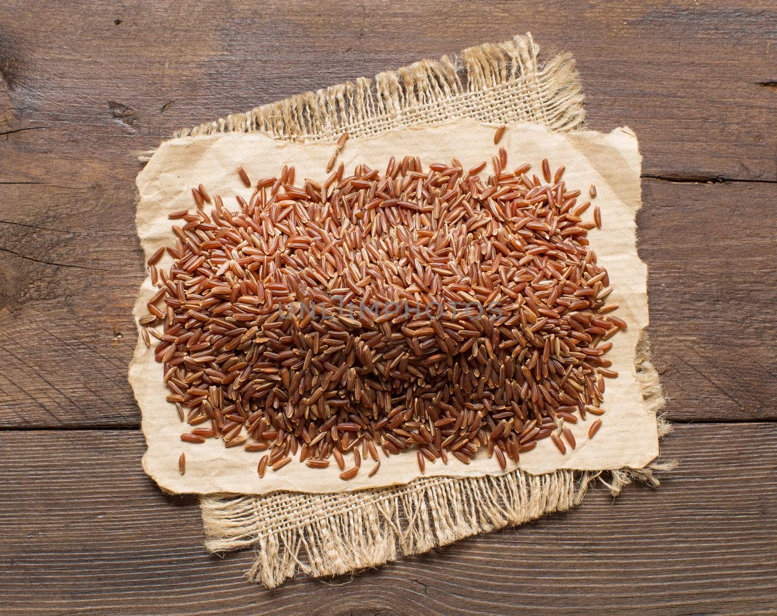 Pile of red rice on a wooden table top view