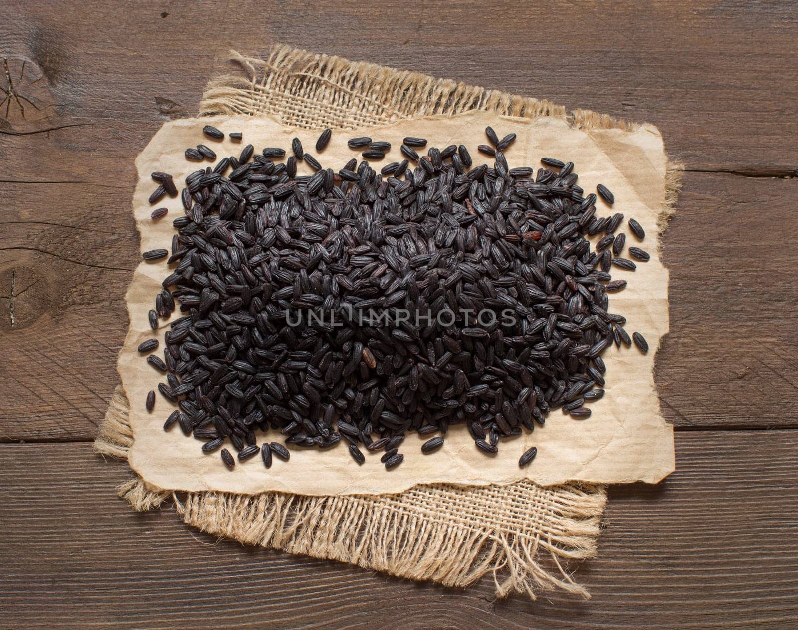 A pile of black rice on a wooden table top view