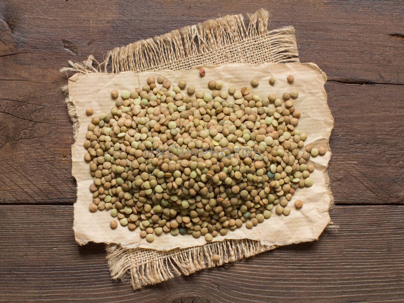 Pile of green lentils on a wooden table top view