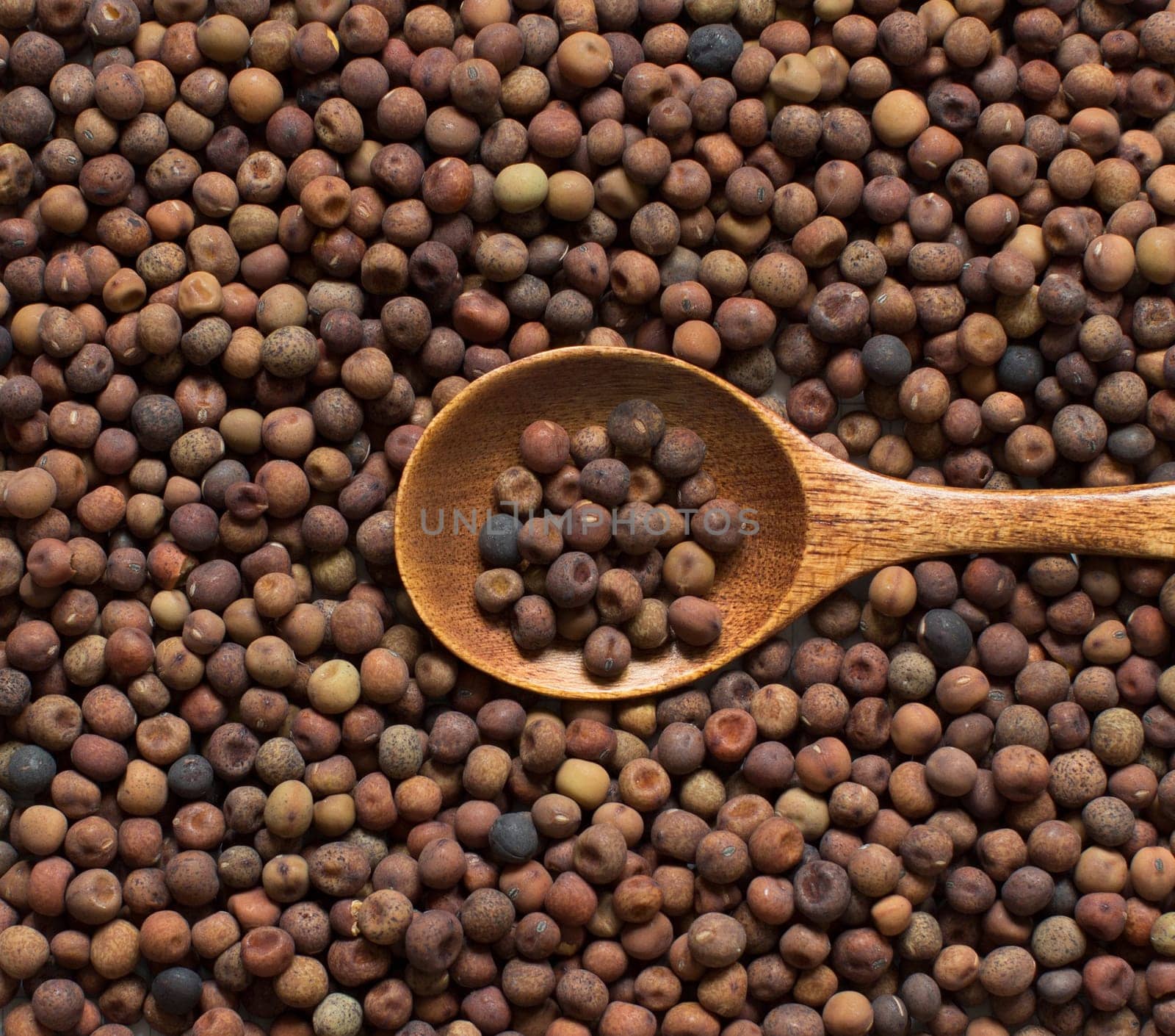 Raw organic roveja beans with a spoon on a wooden table