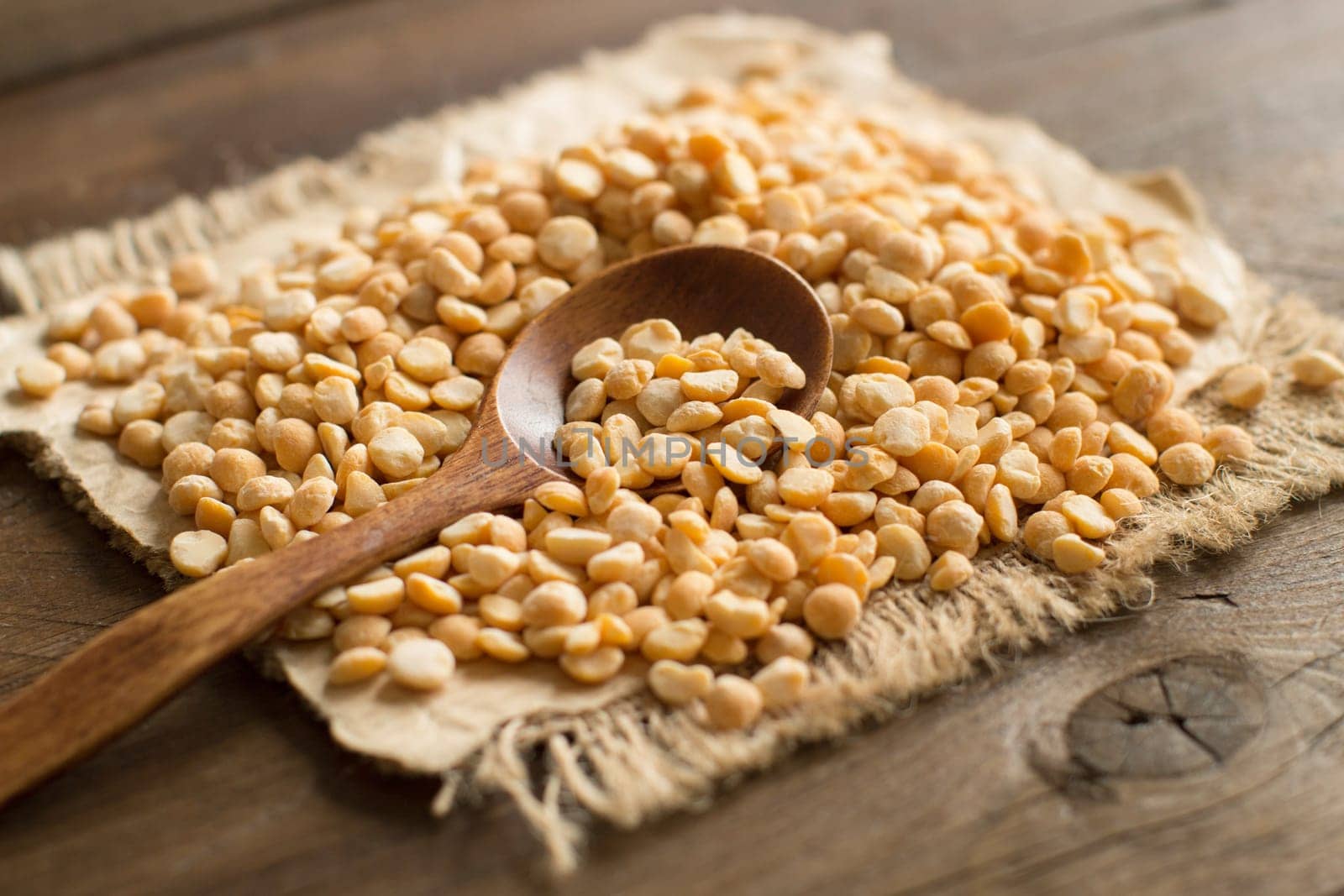 Pile of dried yellow peas with a spoon on a table