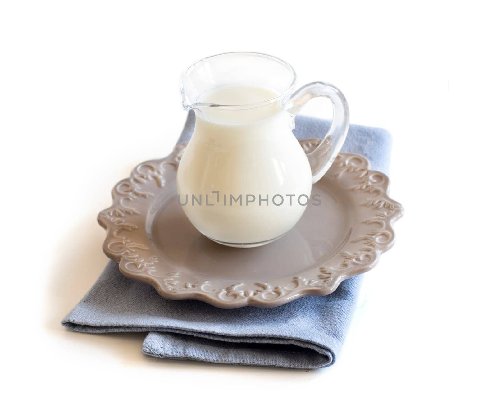 A jar of milk on a plate and napkin isolated on white