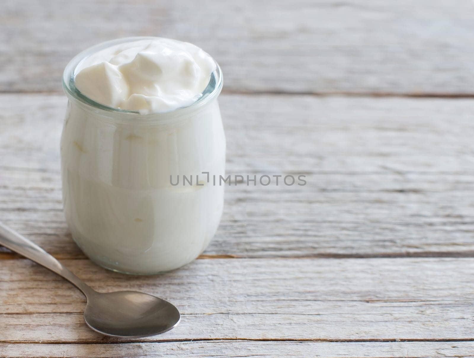 Jar of fresh greek yogurt on a wooden table