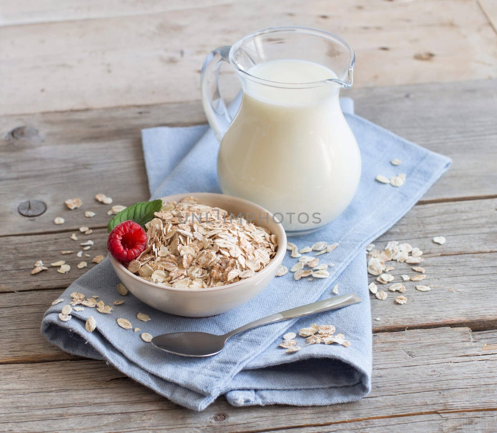 Rolled oats in a bowl with berries and milk on wood