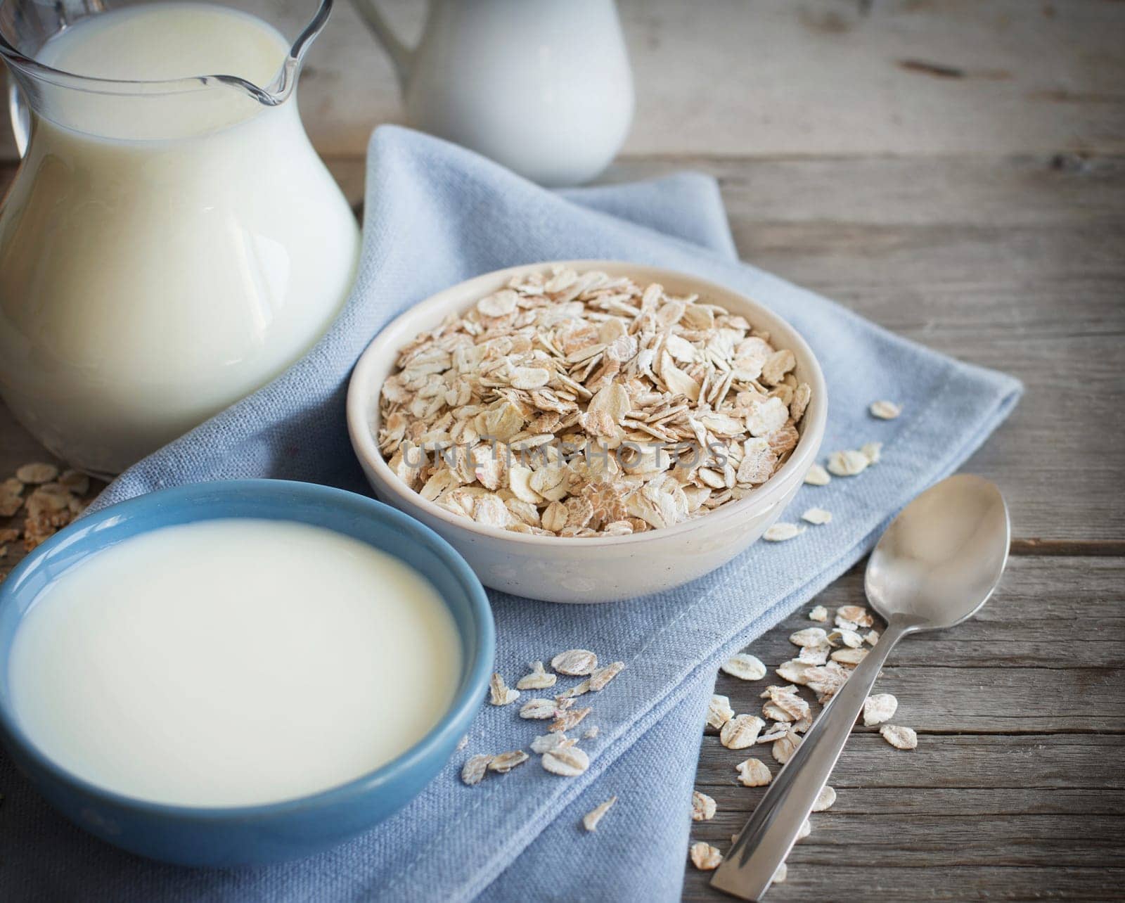 Rolled oats in a bowl and milk on a wooden table