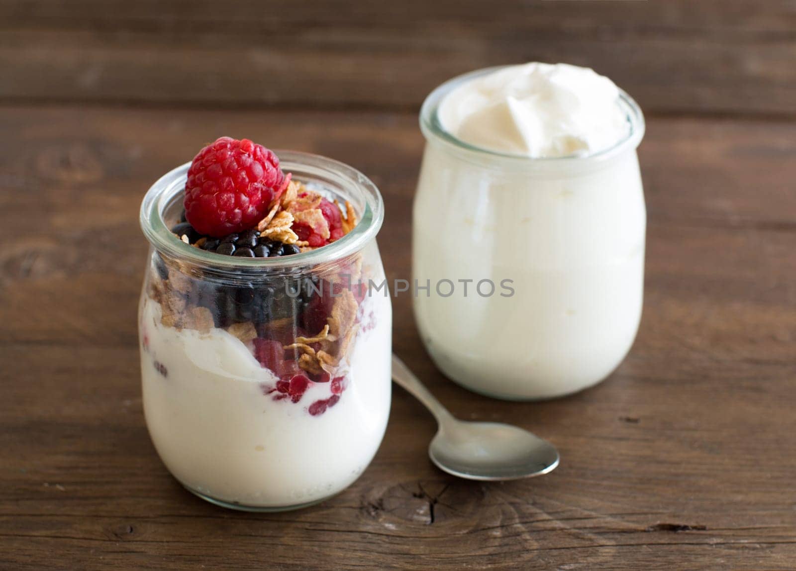 Berries, flakes and fresh greek yogurt on a wooden table