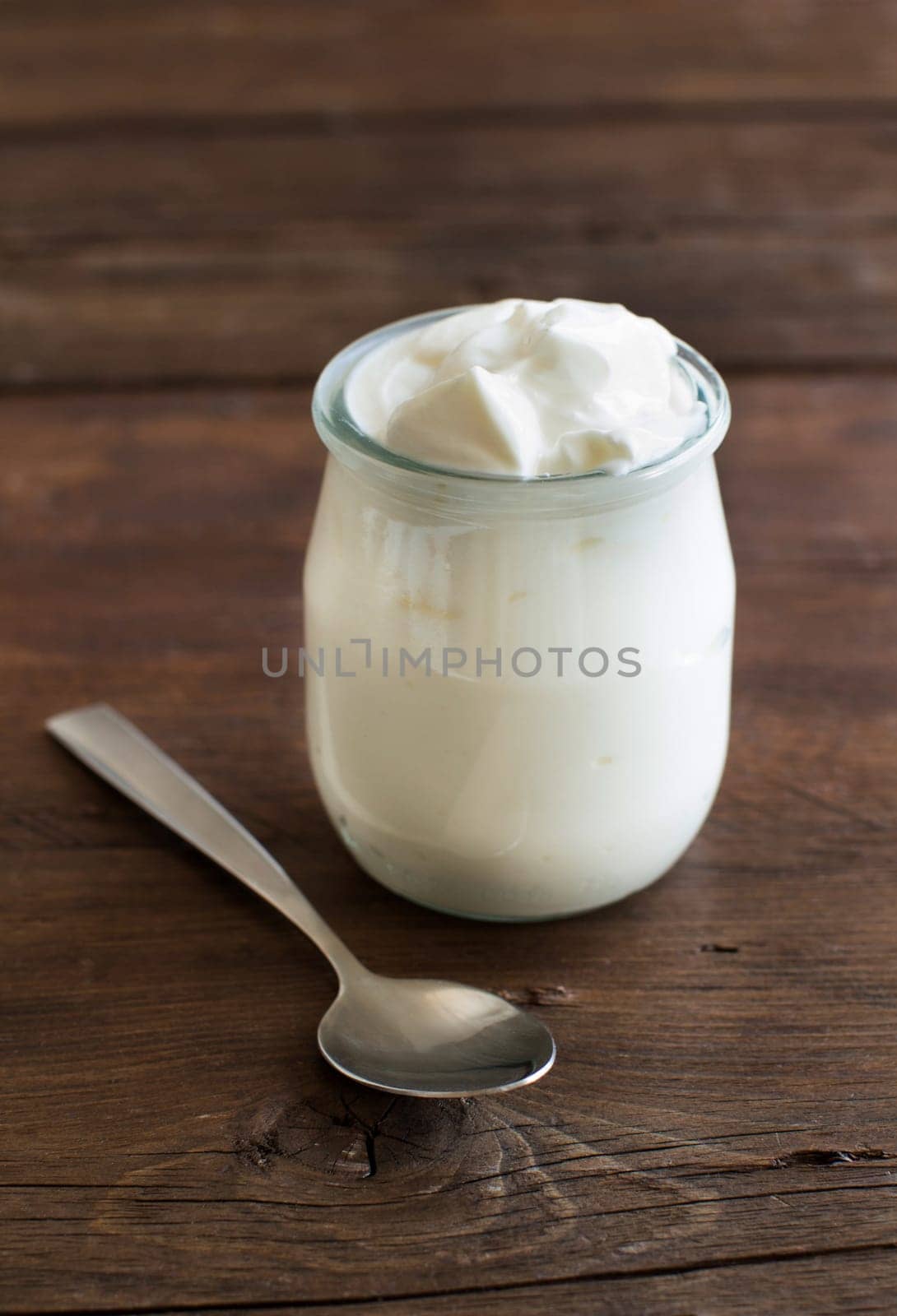 Jar of fresh greek yogurt on a wooden table