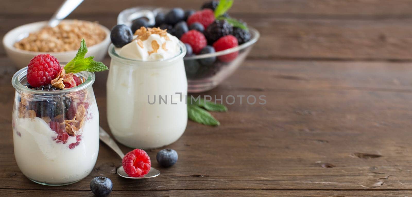 Berries, flakes and fresh greek yogurt on a wooden table