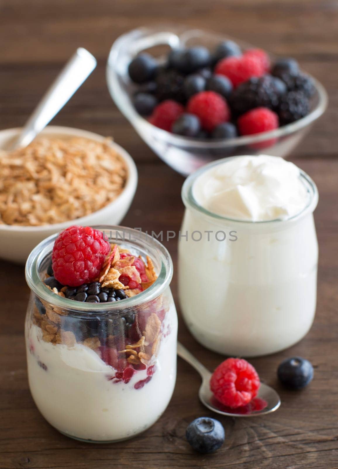 Berries, flakes and fresh greek yogurt on a wooden table