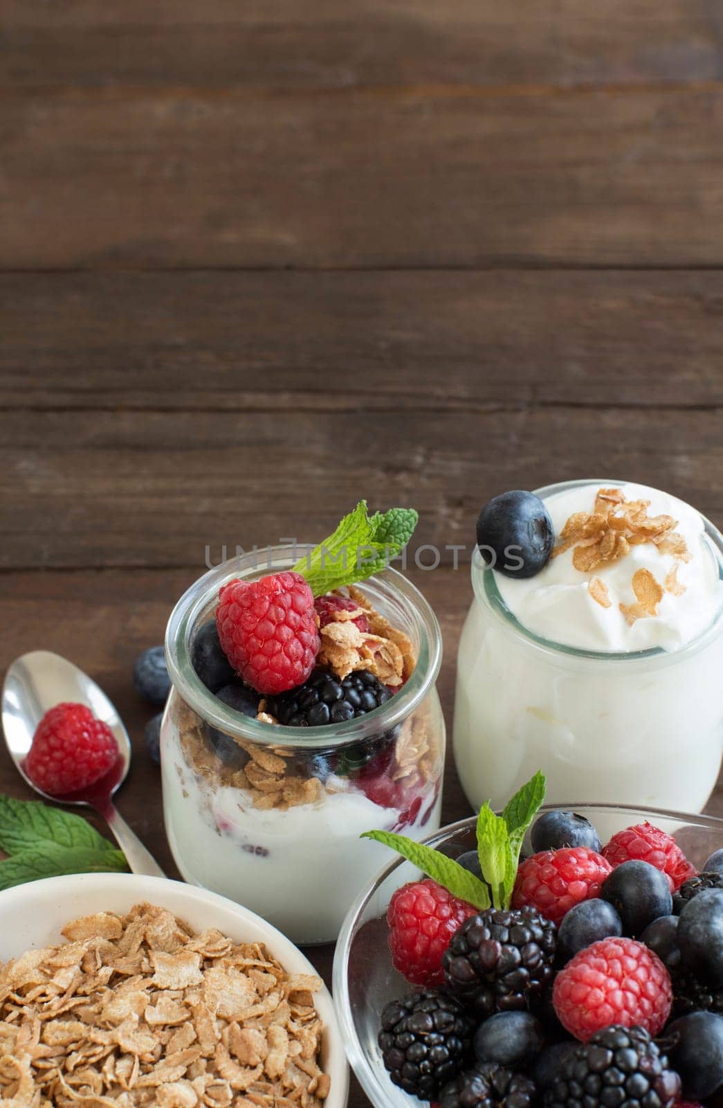 Berries, flakes and fresh greek yogurt on a wooden table
