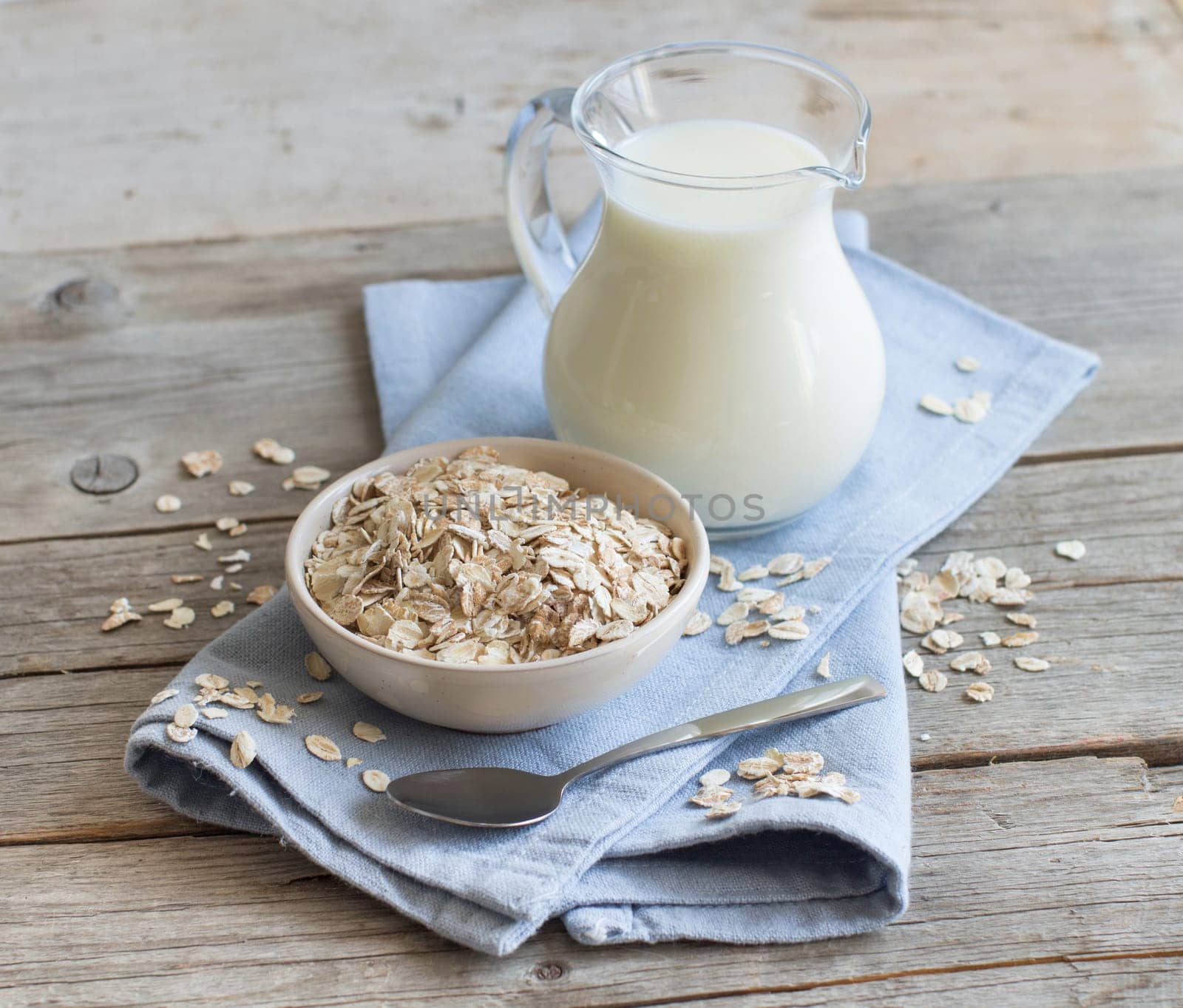 Rolled oats in a bowl and milk on a wooden table