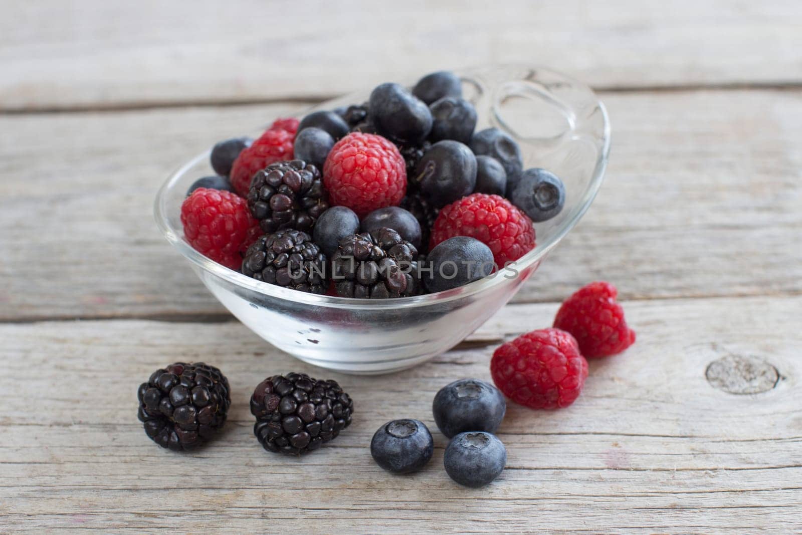 Fresh berries in a bowl on the wooden table
