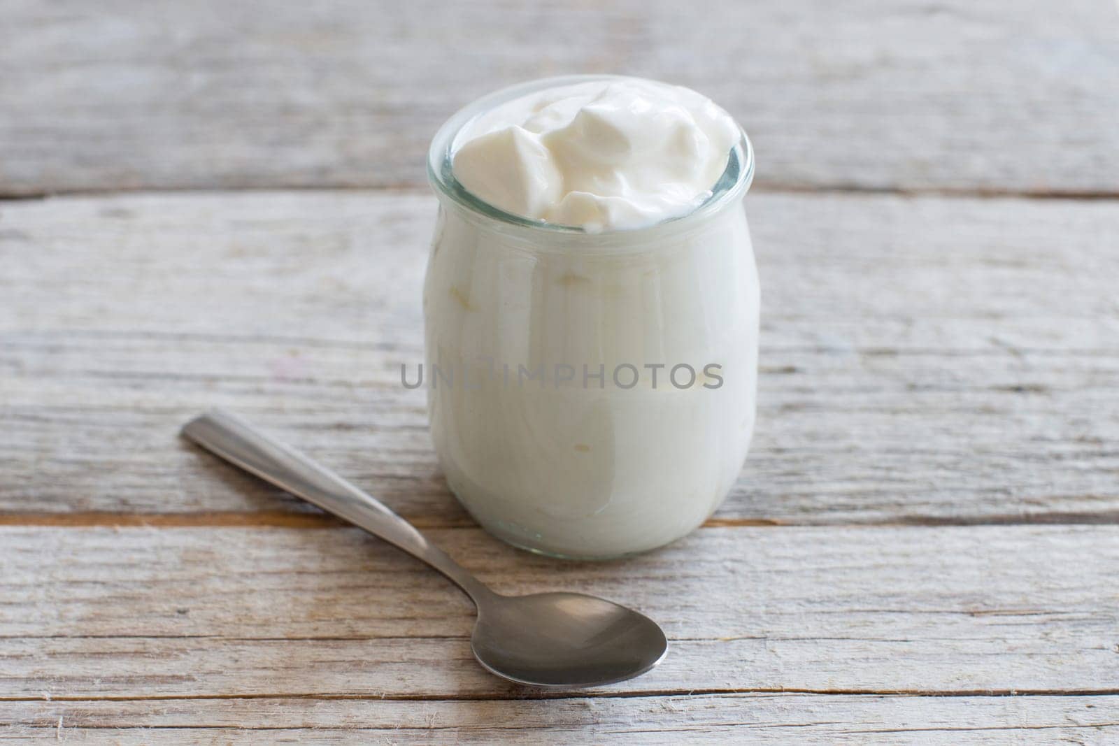 Jar of fresh greek yogurt on a wooden table