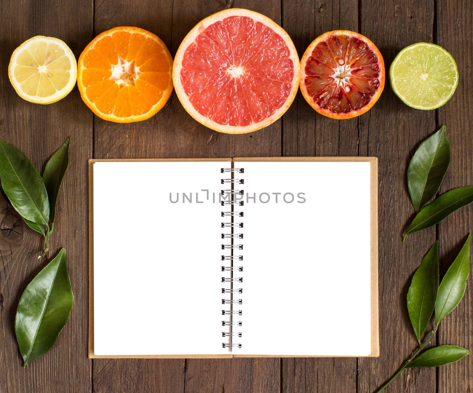Fresh citrus fruits and notebook on a wooden table