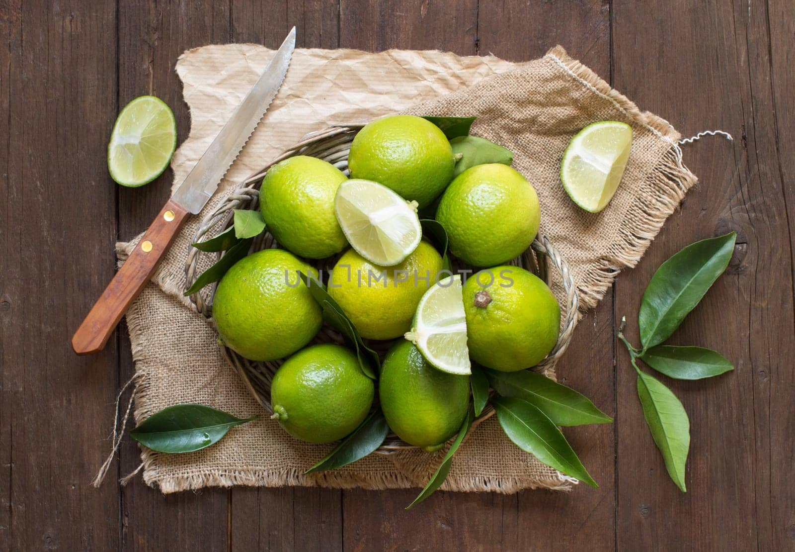 Fresh limes with knife on a wooden table