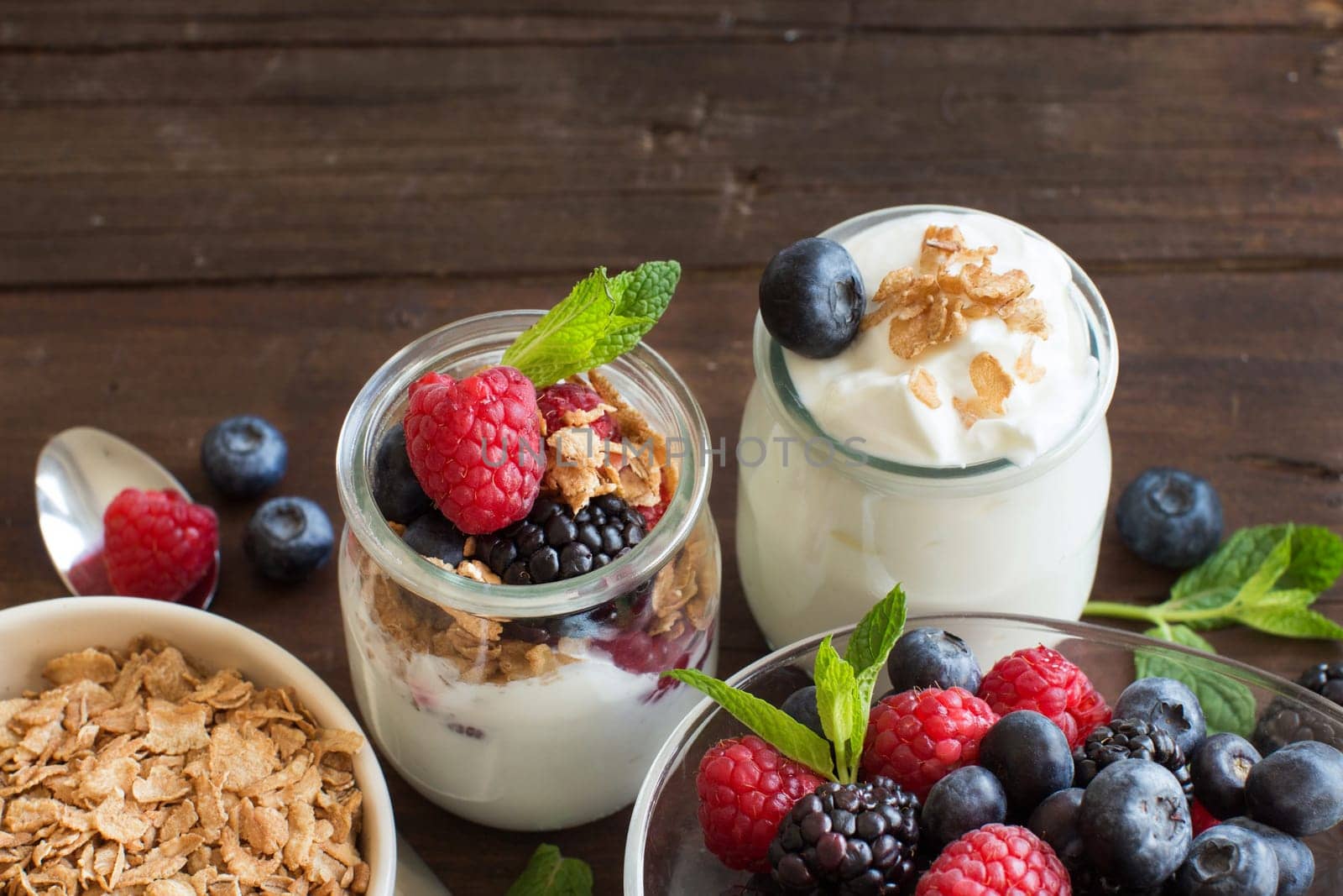 Berries, flakes and fresh greek yogurt on a wooden table