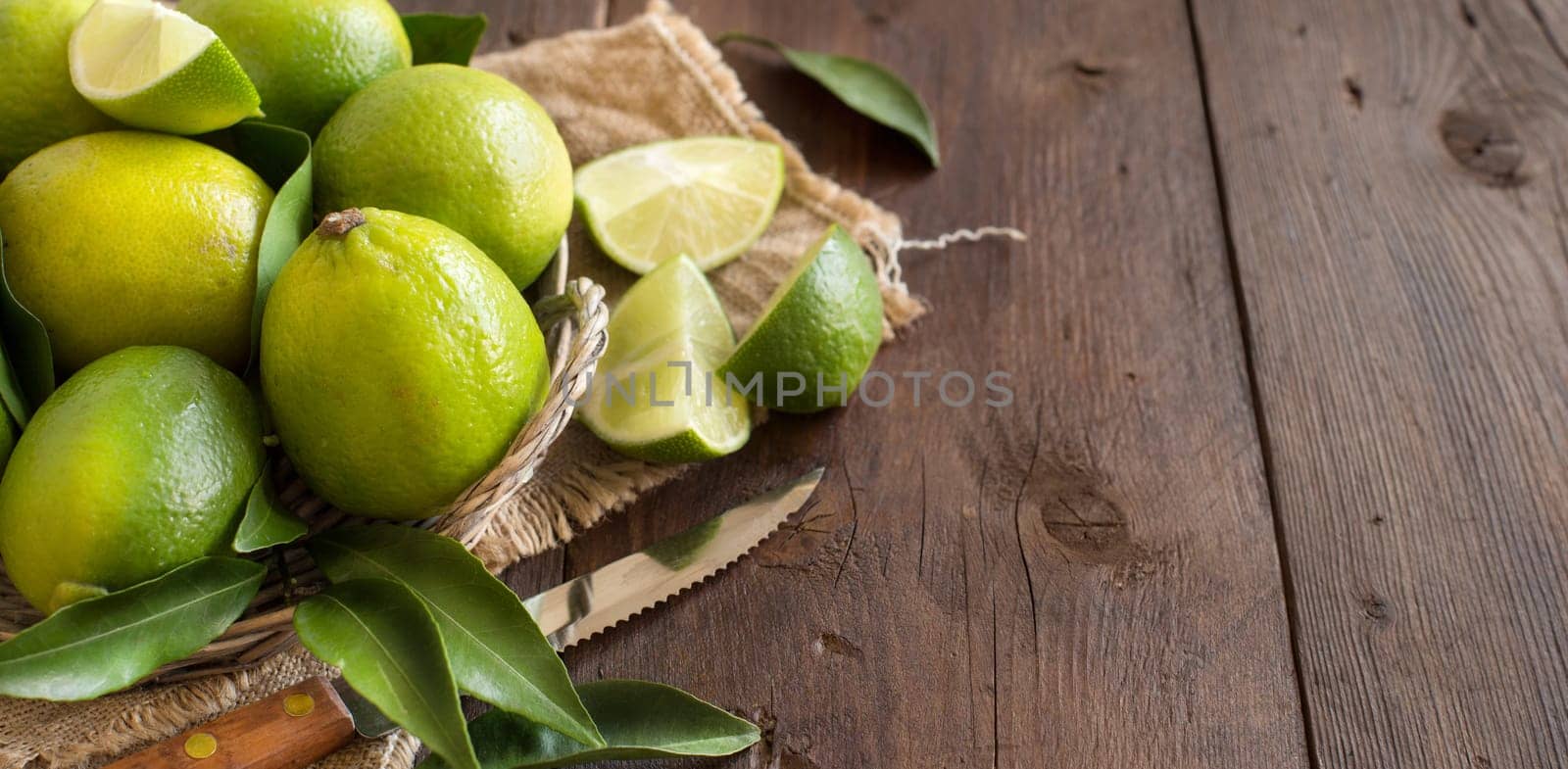 Fresh limes with knife on a wooden table