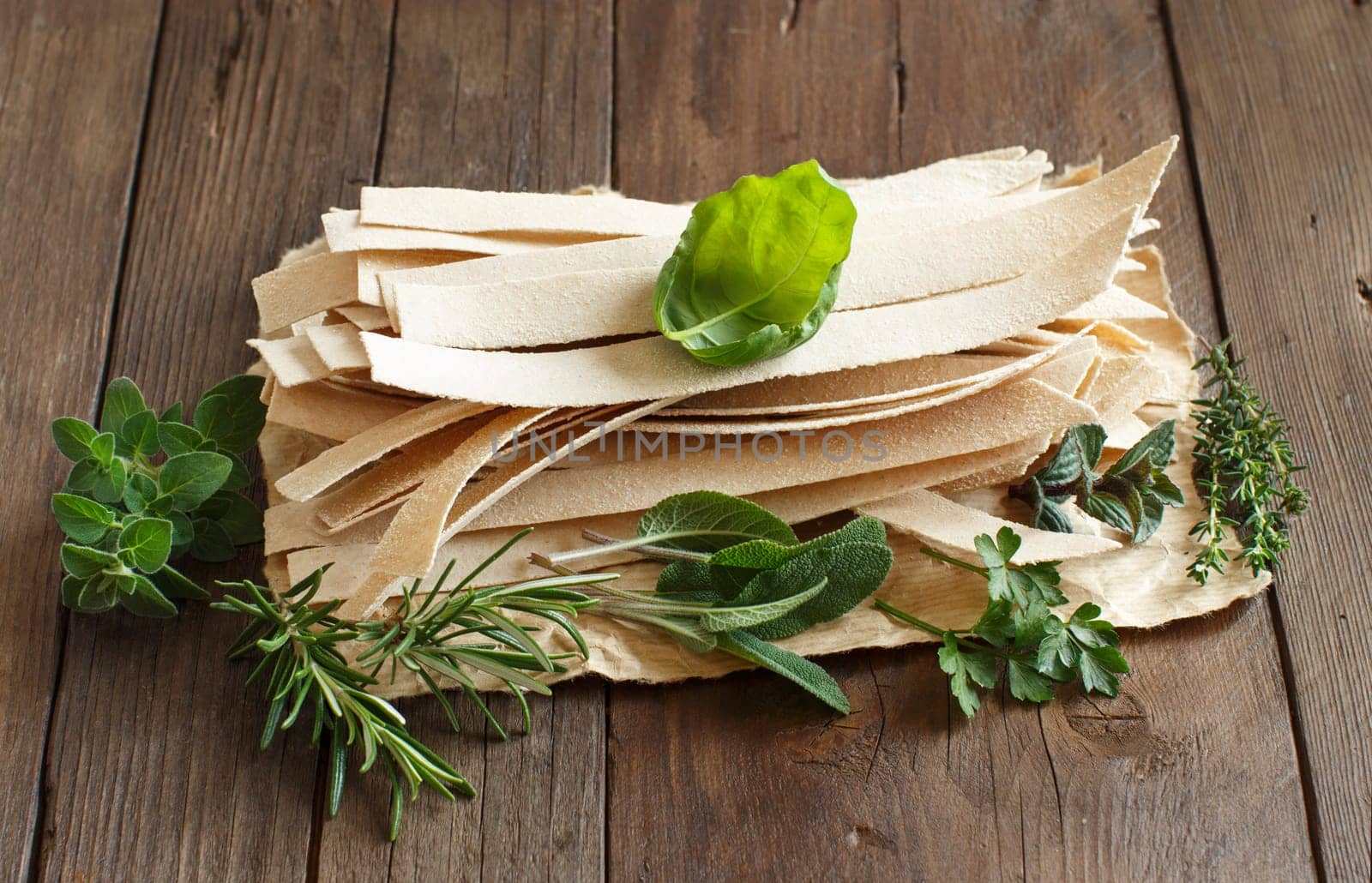 Wholegrain artisan pasta and herbs on old wooden table
