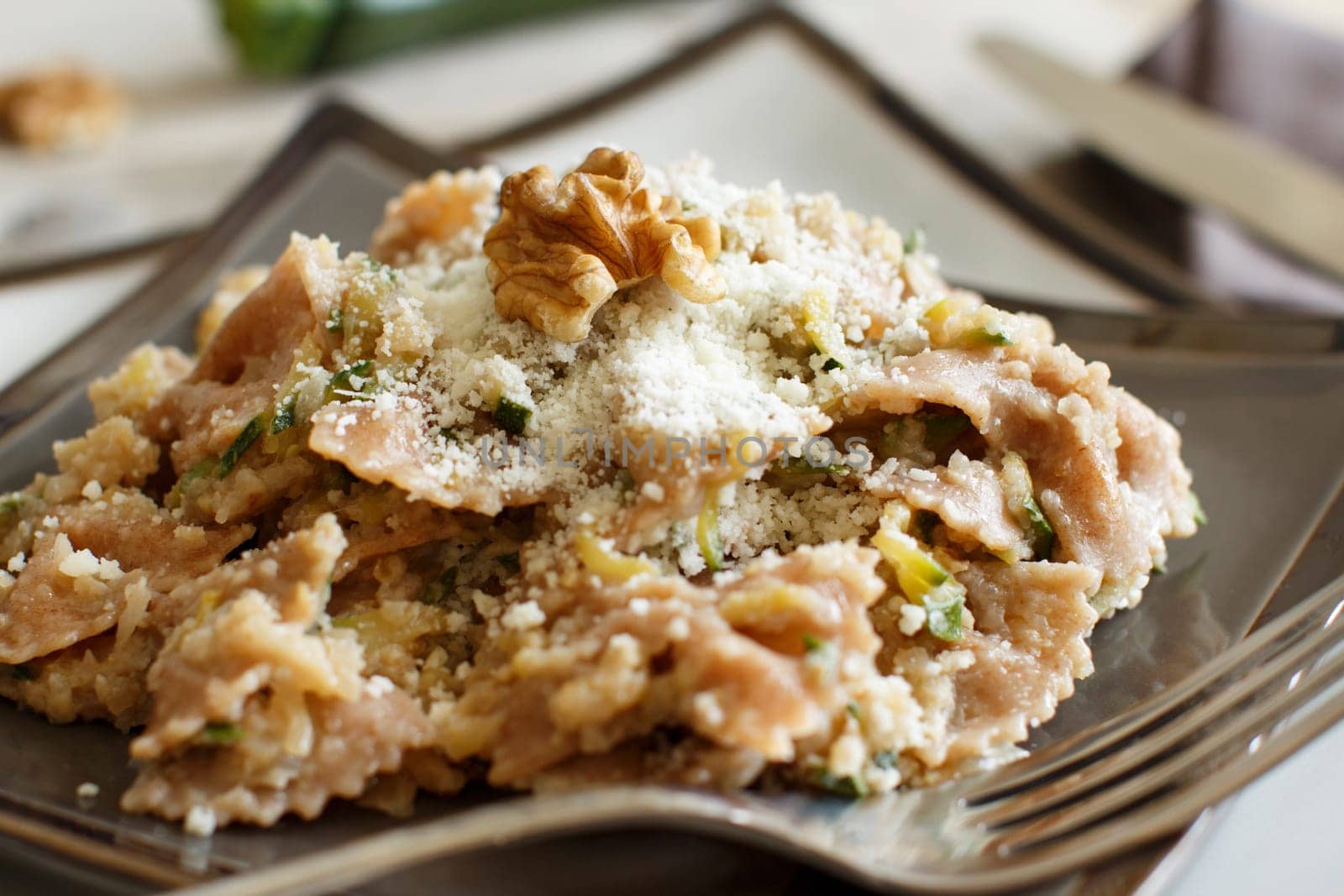 Wholegrain Pasta with topinambur cream, walnuts and zucchine closeup