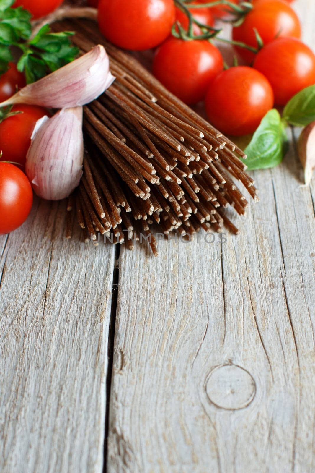 Wholegrain rye spaghetti, tomatoes and herbs on wood