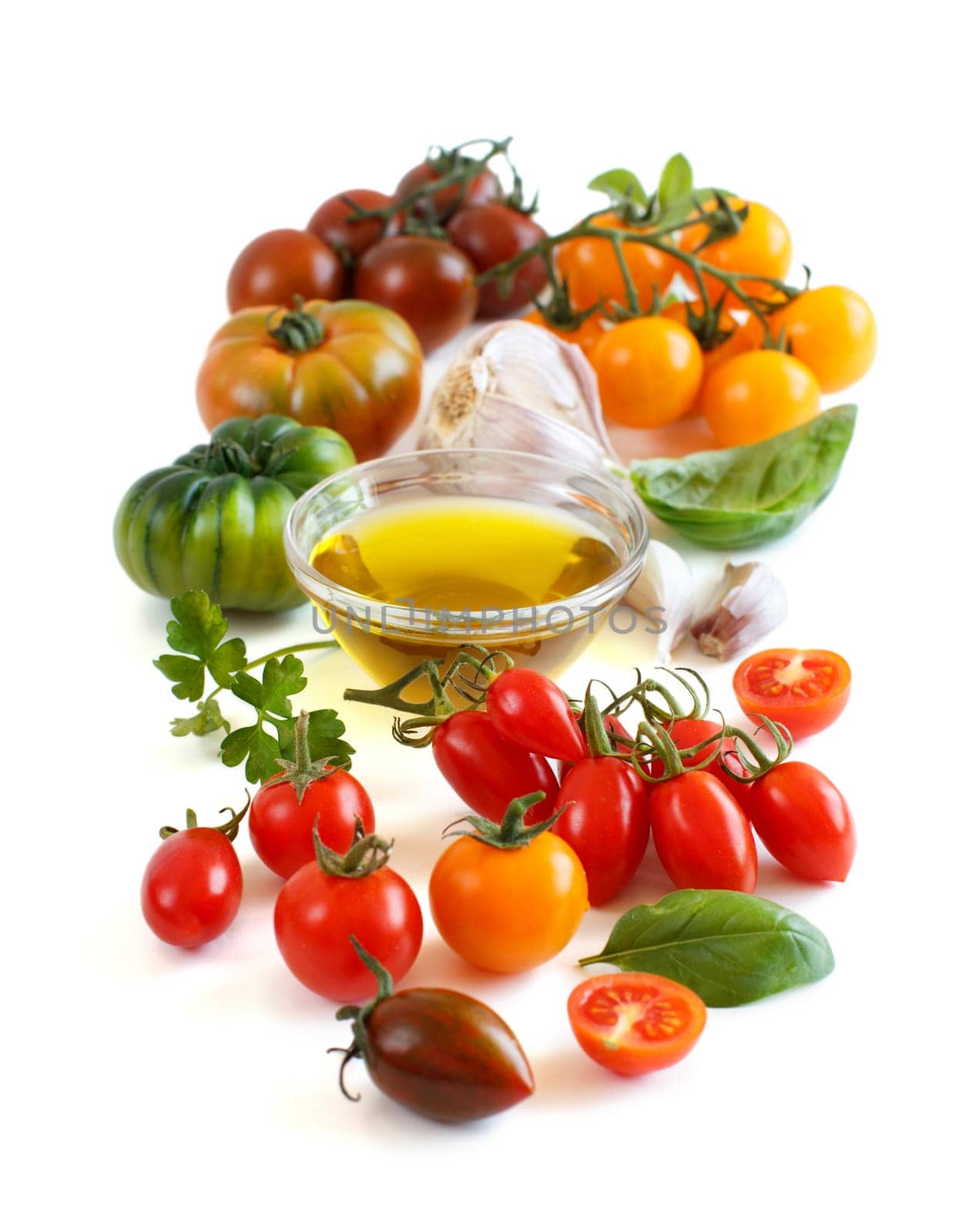 Colorful tomatoes, garlic, herbs and oilve oil isolated on white