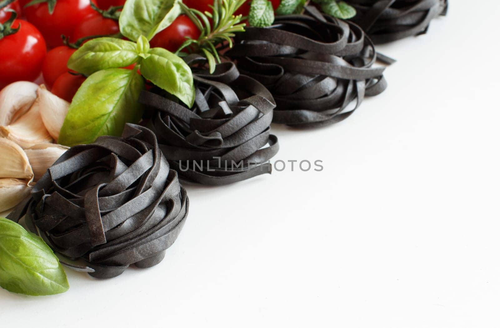 Black Tagliatelle pasta with cherry tomatoes, garlic and herbs on wood