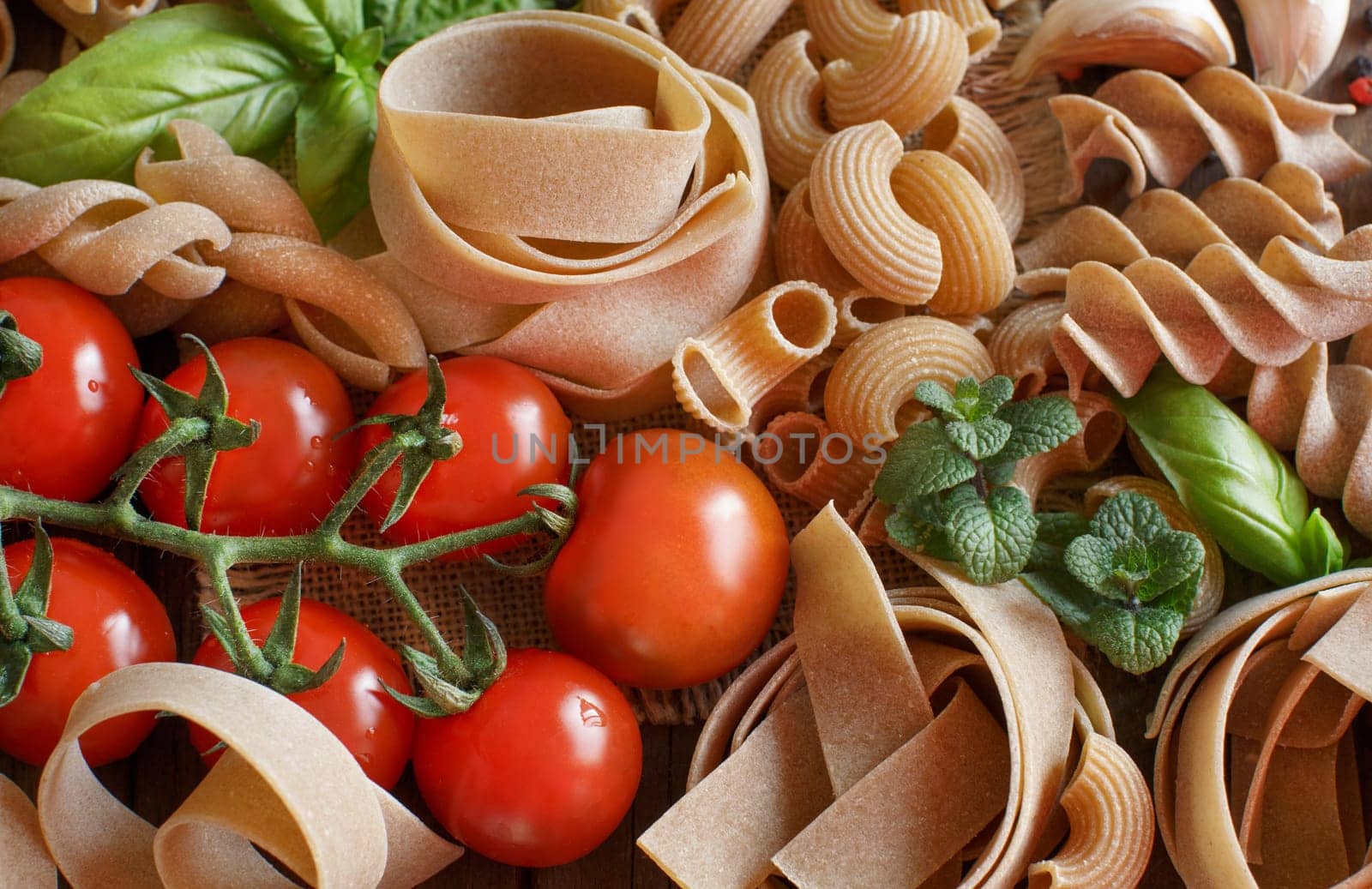 Whole wheat pasta with vegetables and herbs on a wooden background