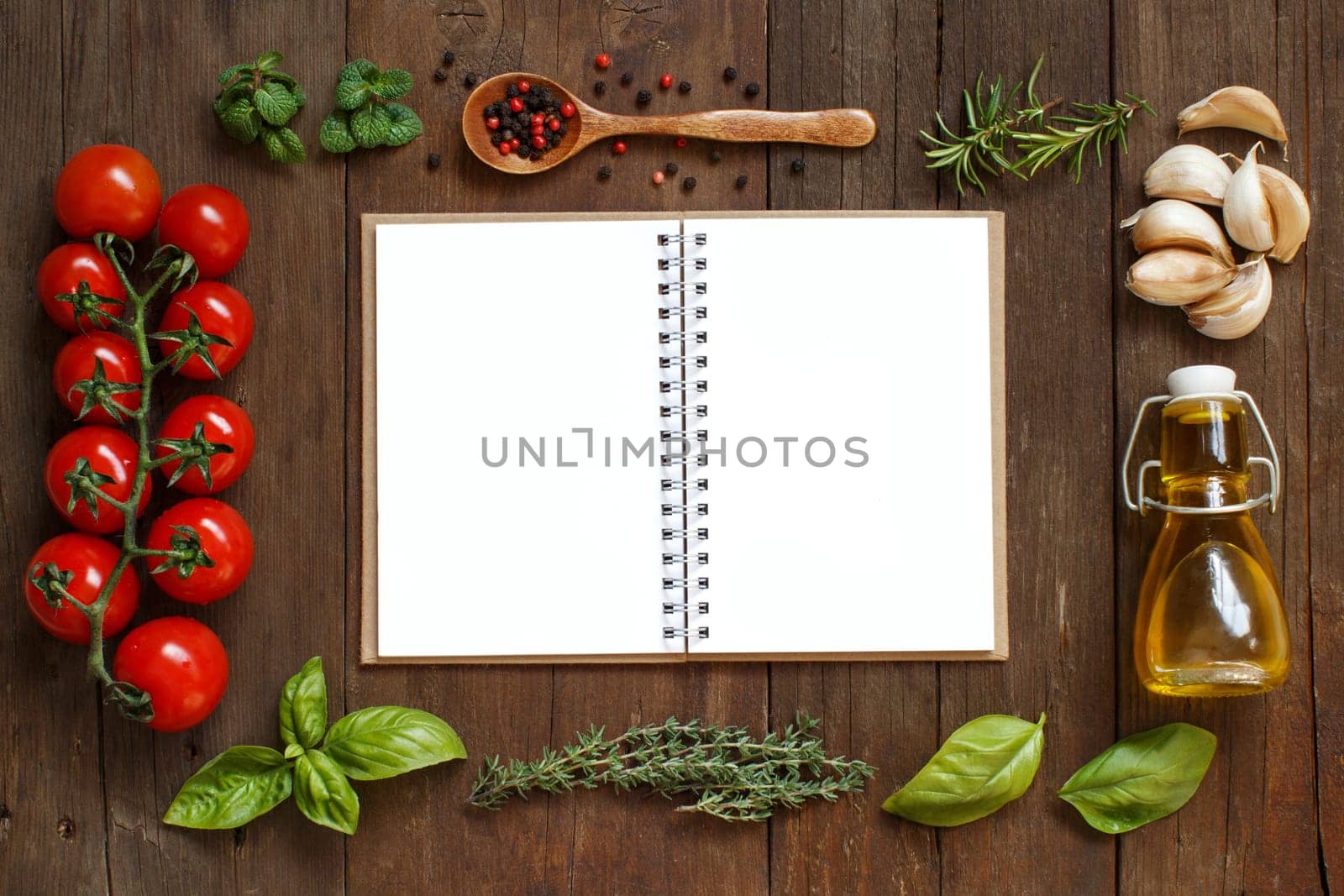 Craft paper with border of vegetables, herbs and olive oil on wooden background