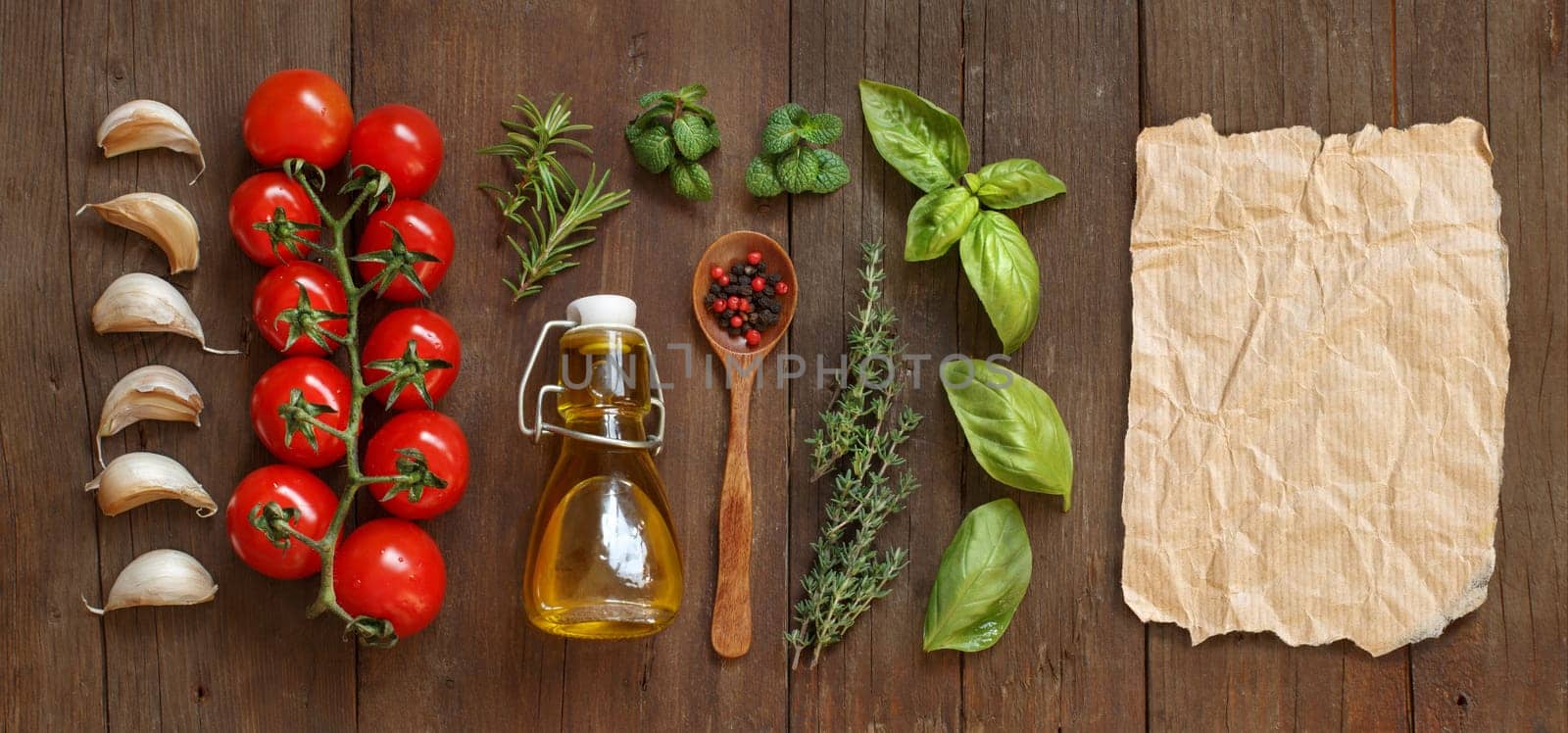 Vegetables, herbs and olive oil with craft paper on wooden background