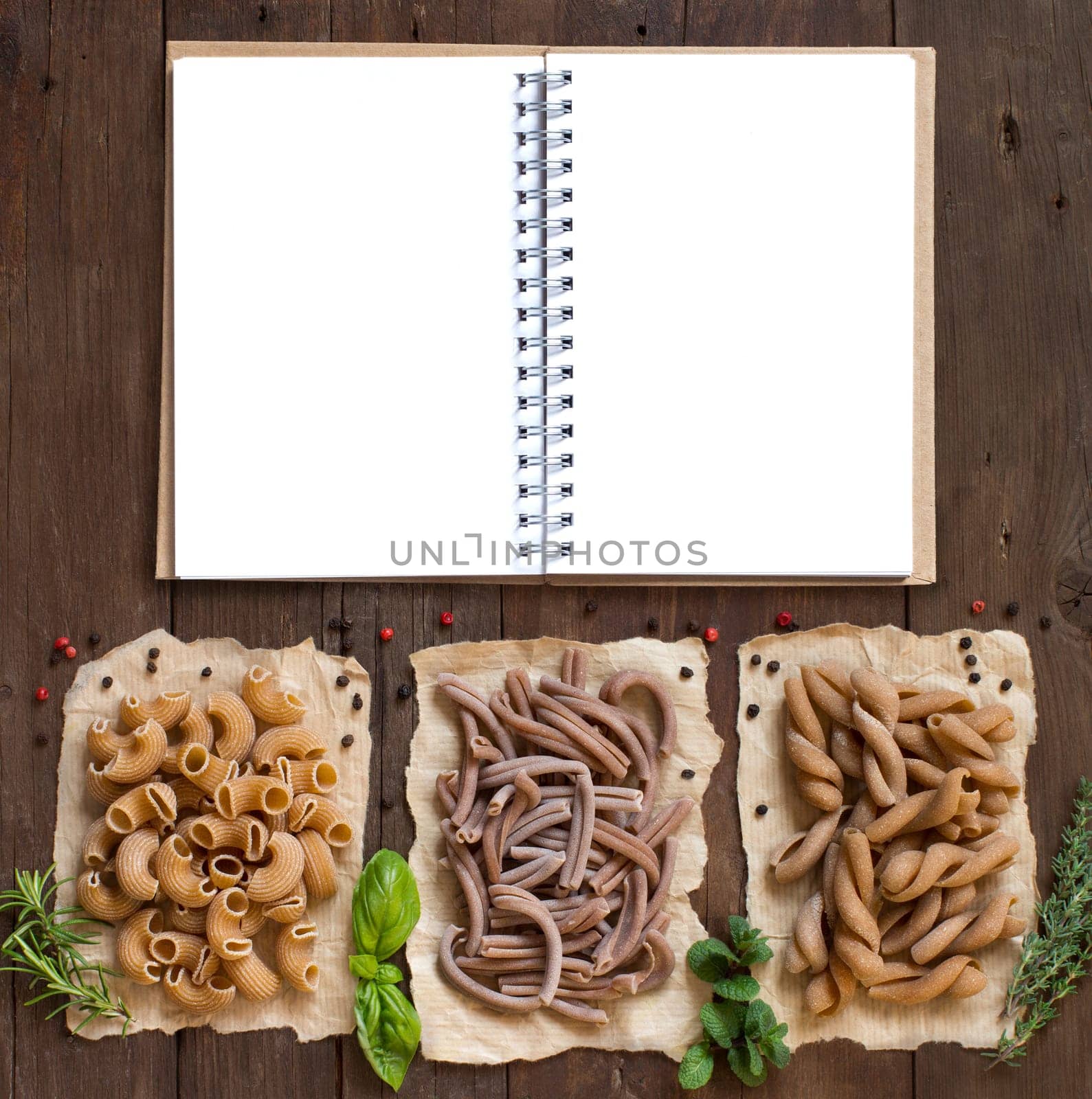 Whole wheat pasta and herbs on a wooden background