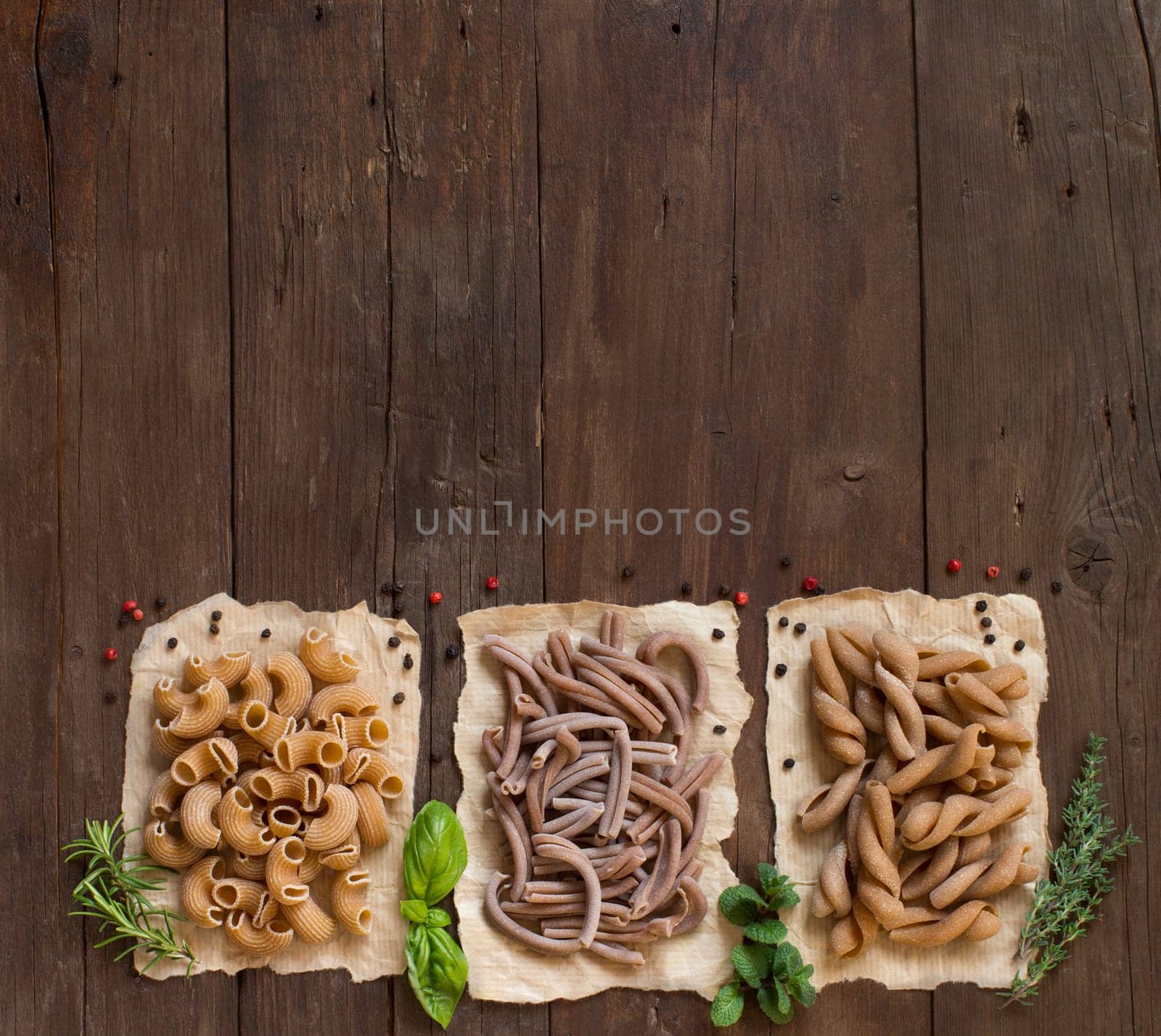 Whole wheat pasta and herbs on a wooden background