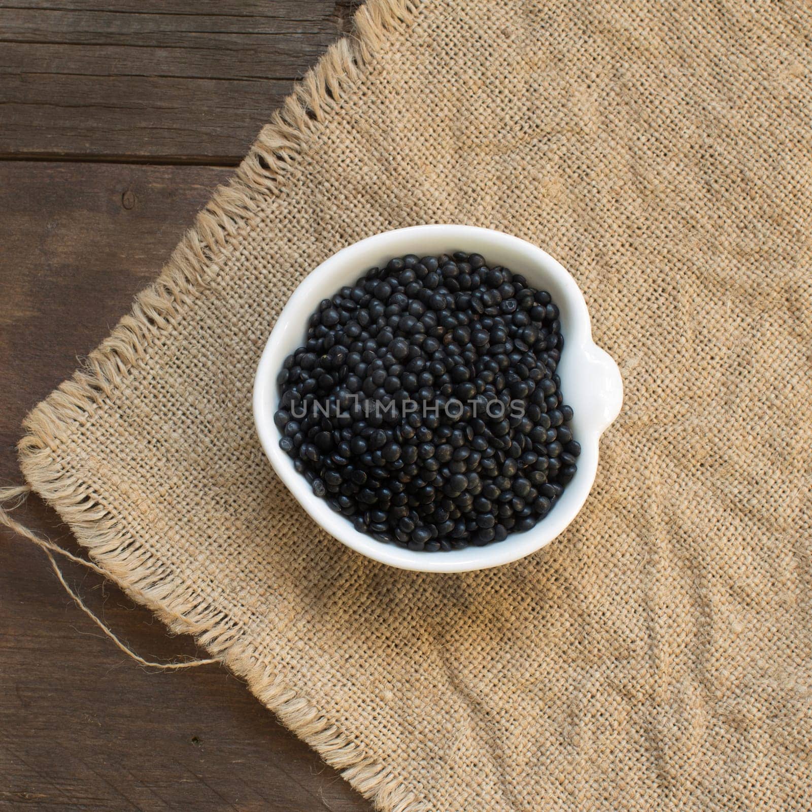 Black lentils in a bowl on a wooden table