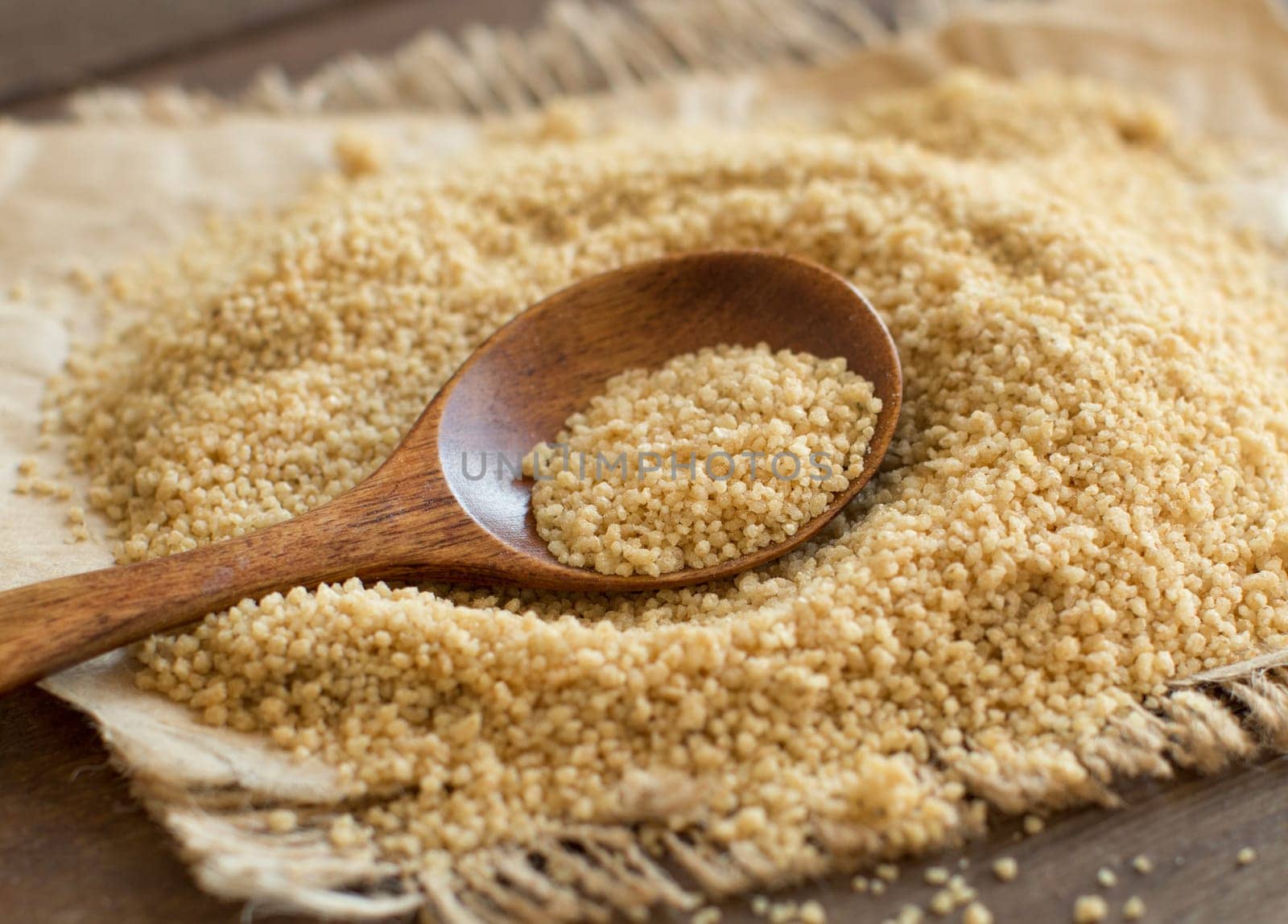 Pile of whole wheat CousCous with a spoon close up
