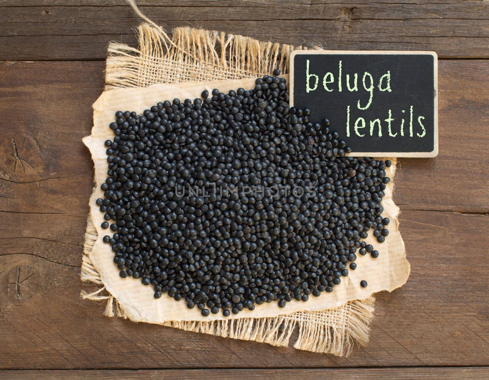 Pile of Black Lentils with a small chalkboard top view