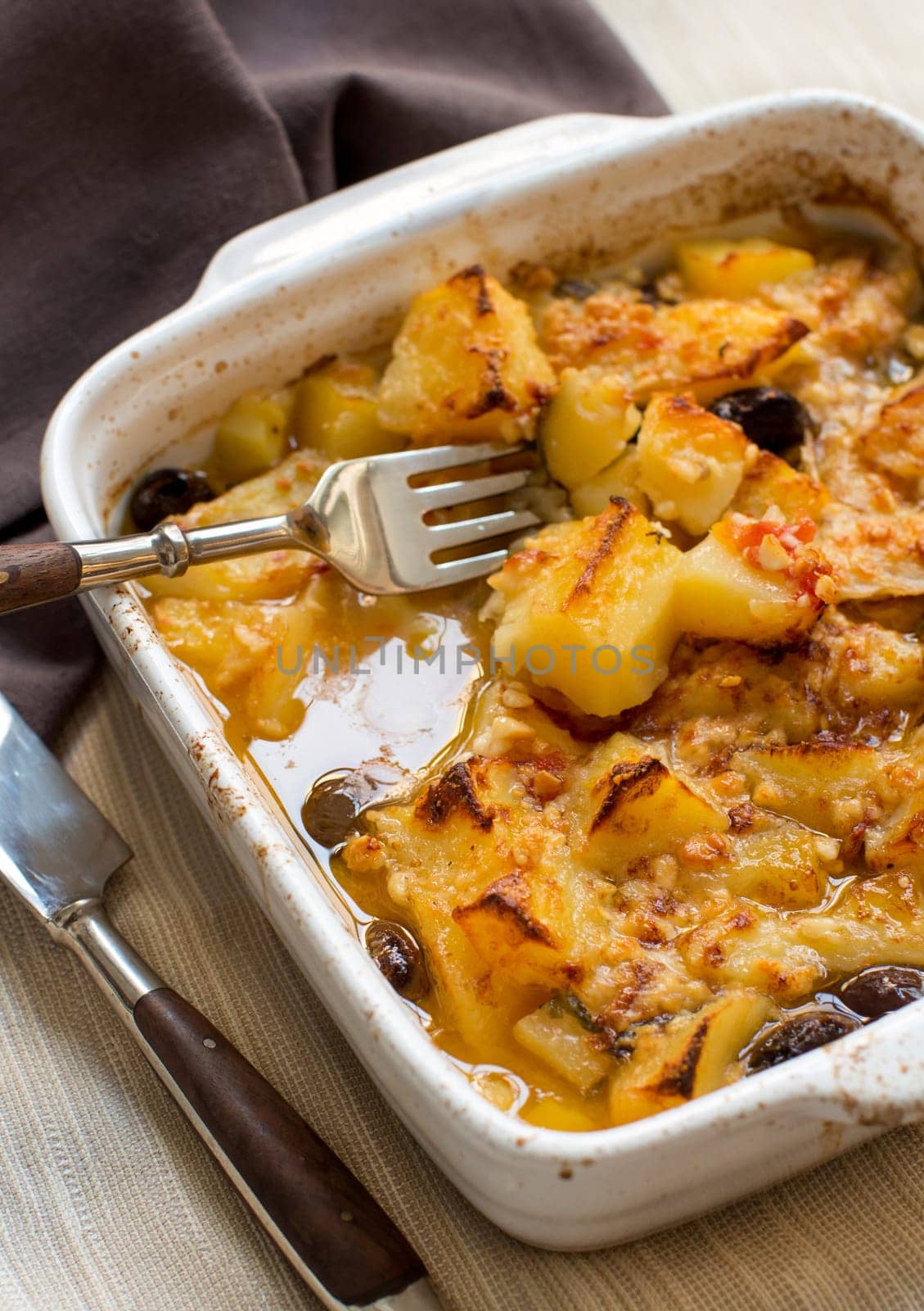 Fish with potatoes and olives cooked in oven in small casserole