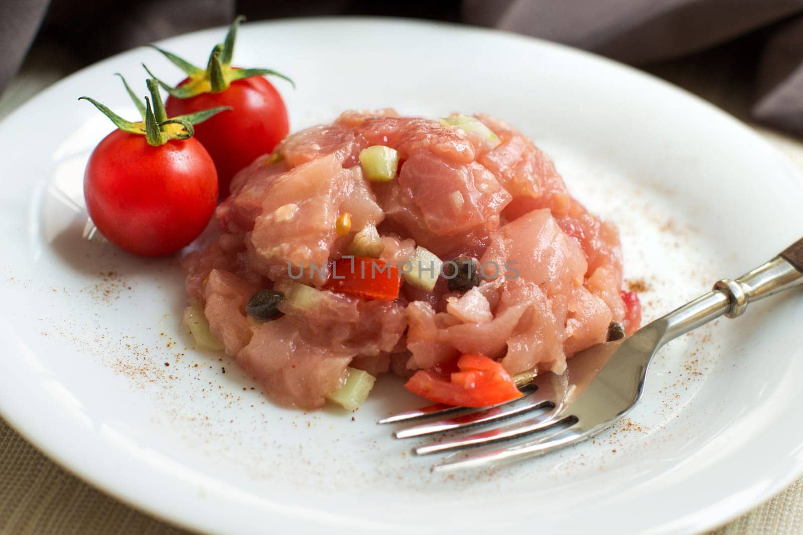 Delicious raw tuna tartare with fork and decorated with cherry tomatoes