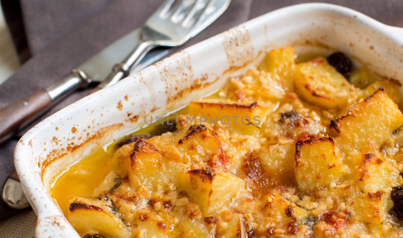 Fish with potatoes and olives cooked in oven in small casserole