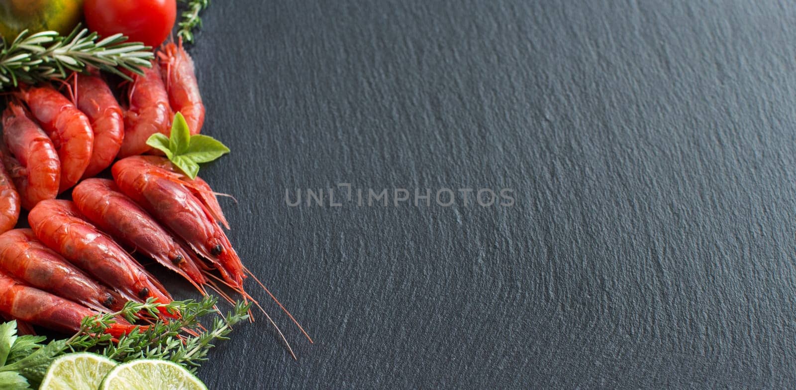Raw shrimps with tomatoes, lime and herbs over dark background