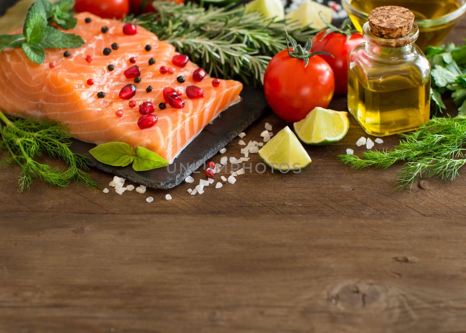 Salmon with vegetables, olive oil and herbs on wood