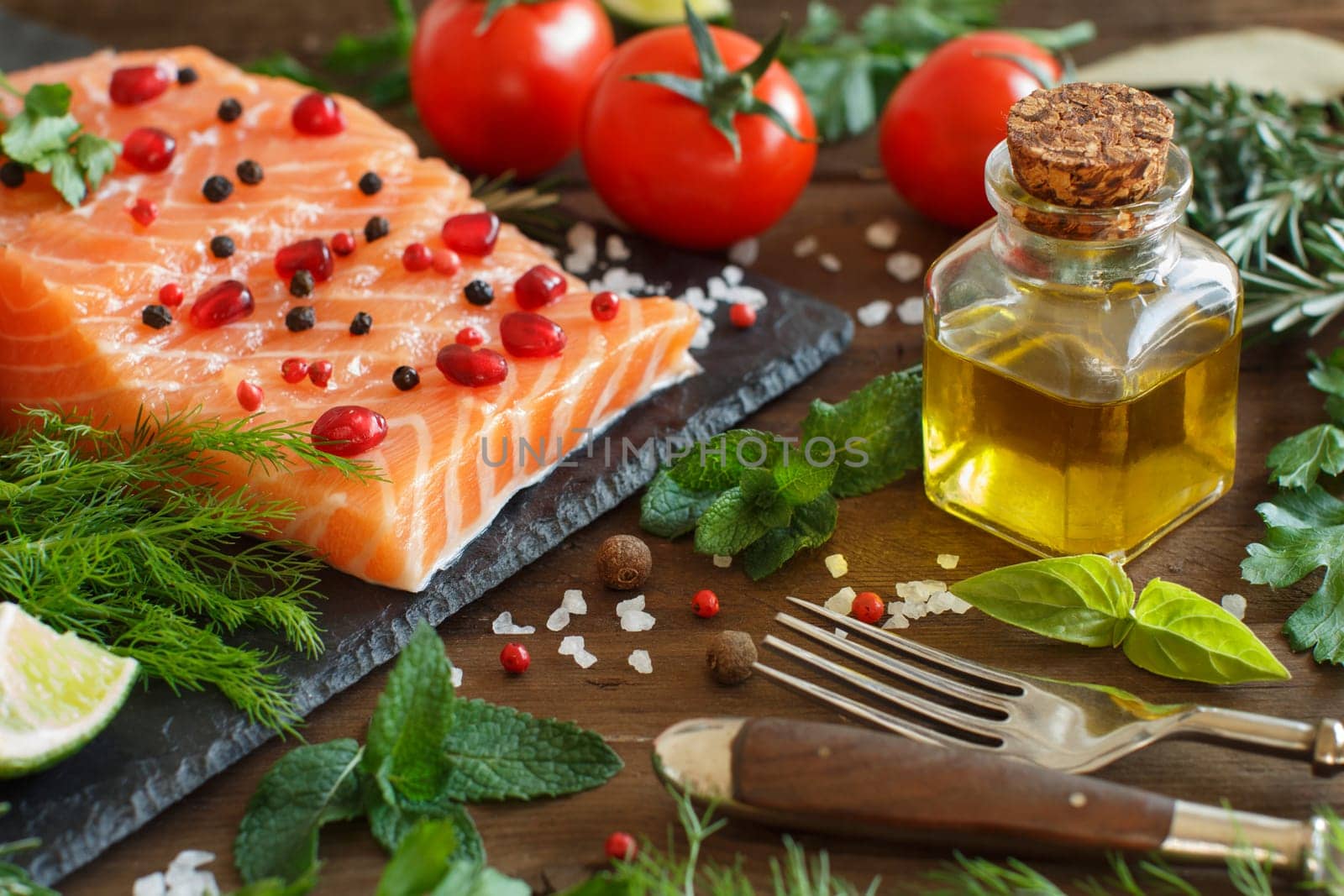 Salmon with vegetables, olive oil and herbs on wood