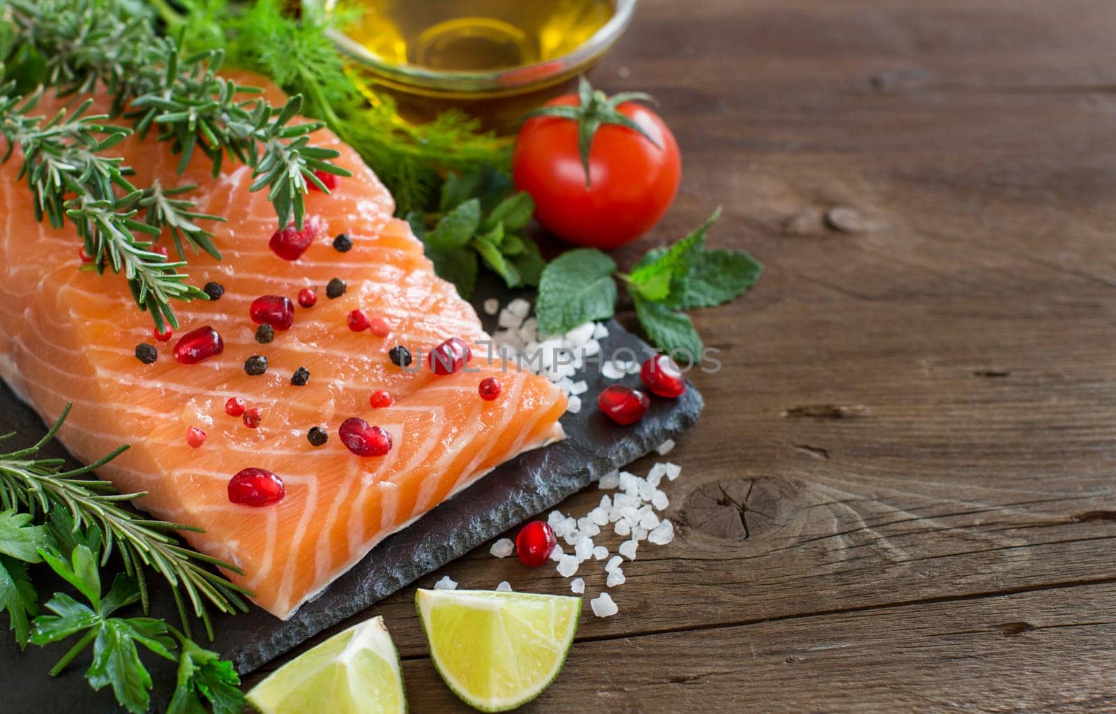Salmon with vegetables, olive oil and herbs on wood