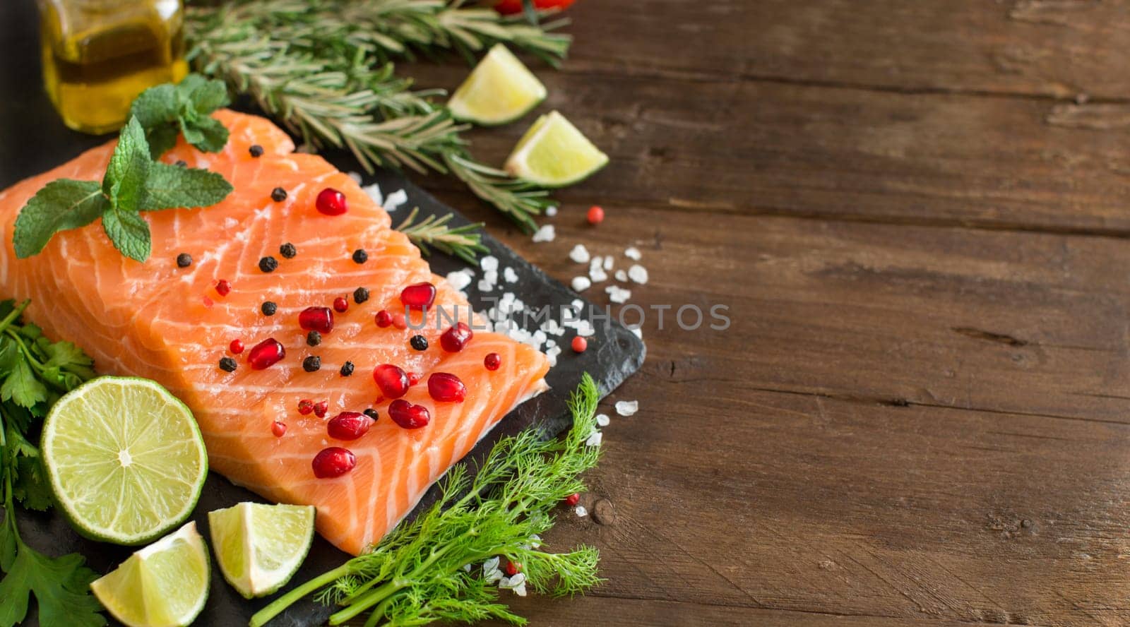 Salmon with vegetables and herbs on wooden background
