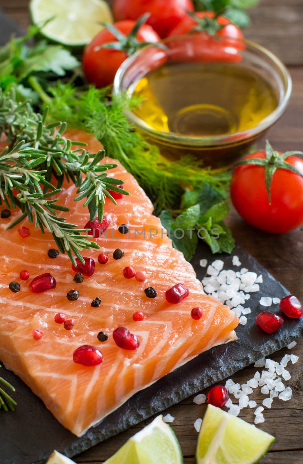Salmon with vegetables, olive oil and herbs on wood