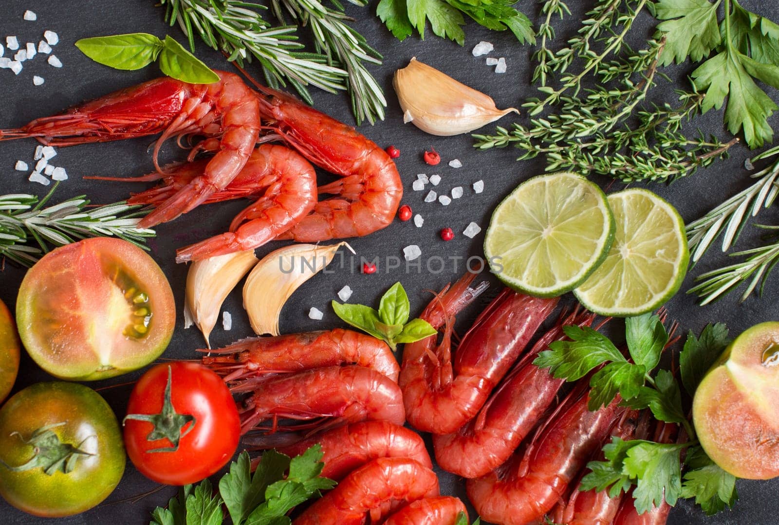 Raw shrimps with tomatoes, lime and herbs over dark background