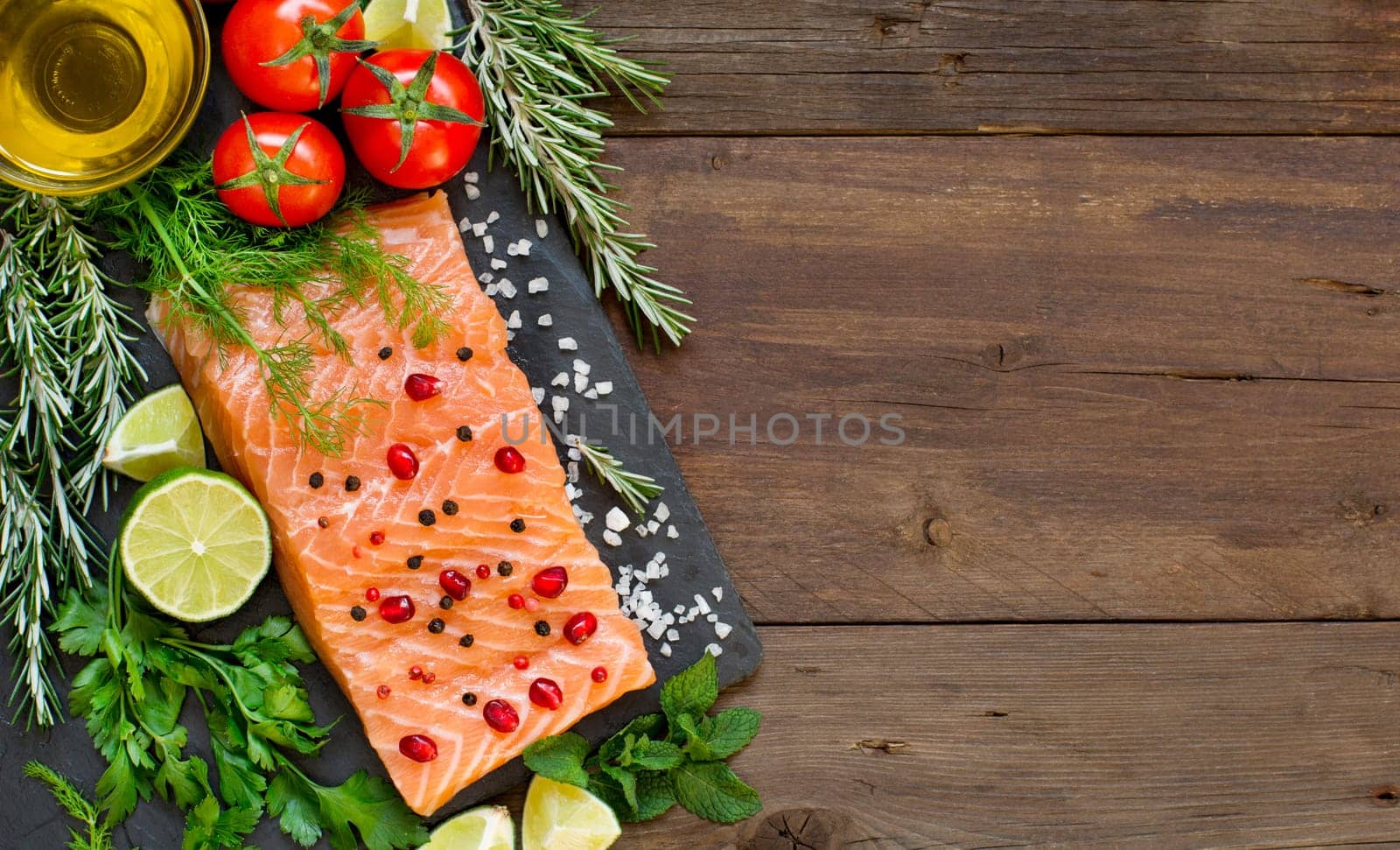 Salmon with vegetables and herbs on wooden background