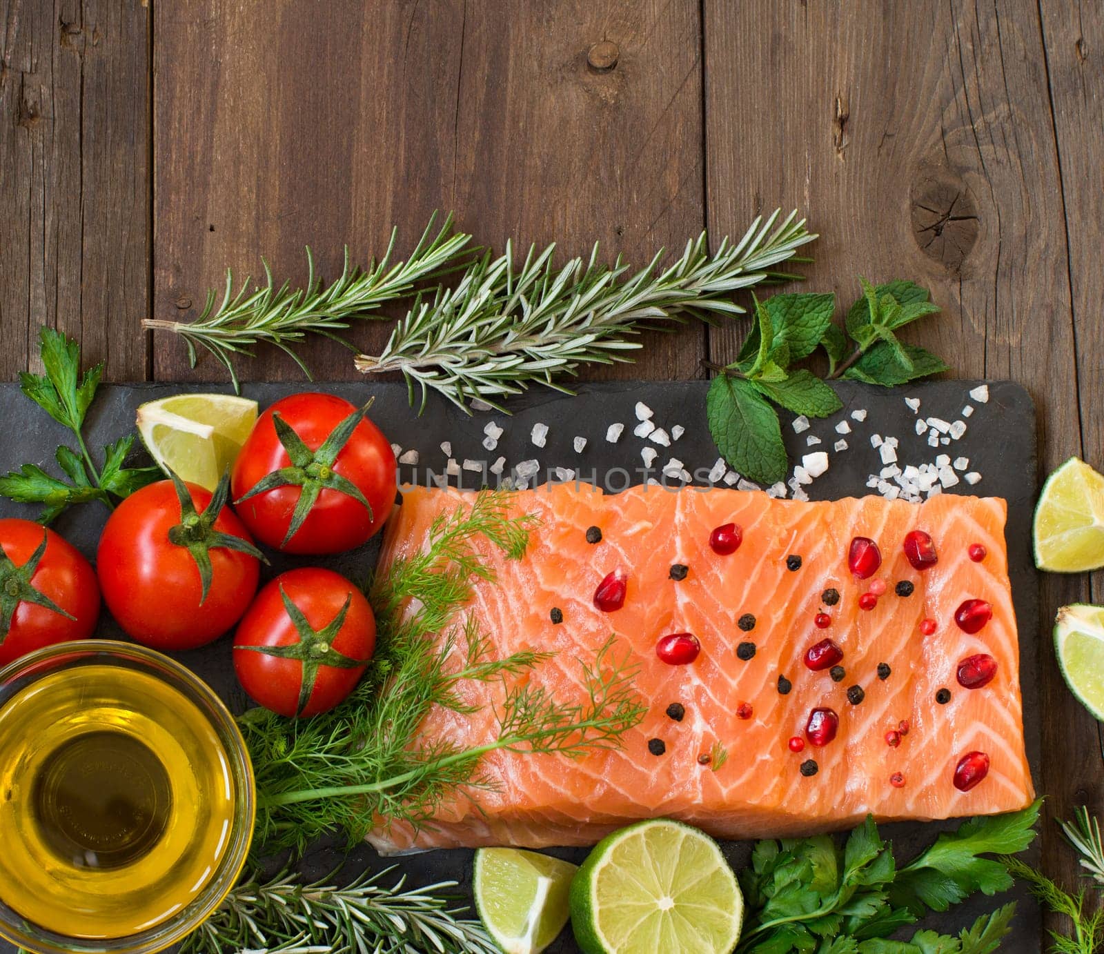 Salmon with vegetables, olive oil and herbs on wood