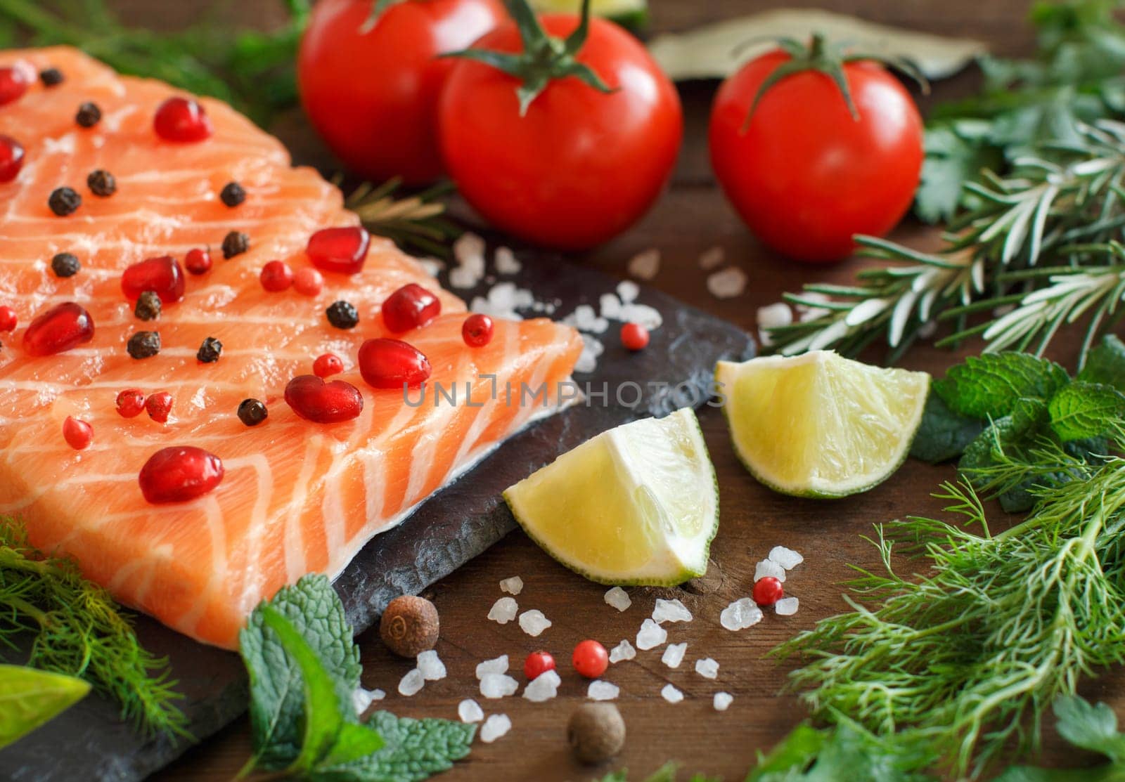 Salmon with vegetables and herbs on wooden background