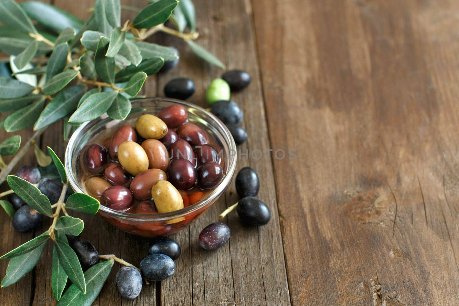 Fresh olives and olive branch on rustic wood background