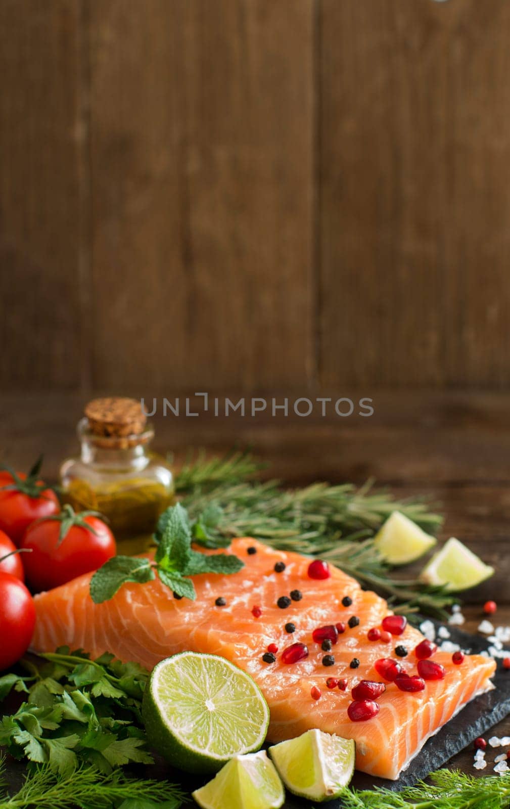 Salmon with vegetables, olive oil and herbs on wood